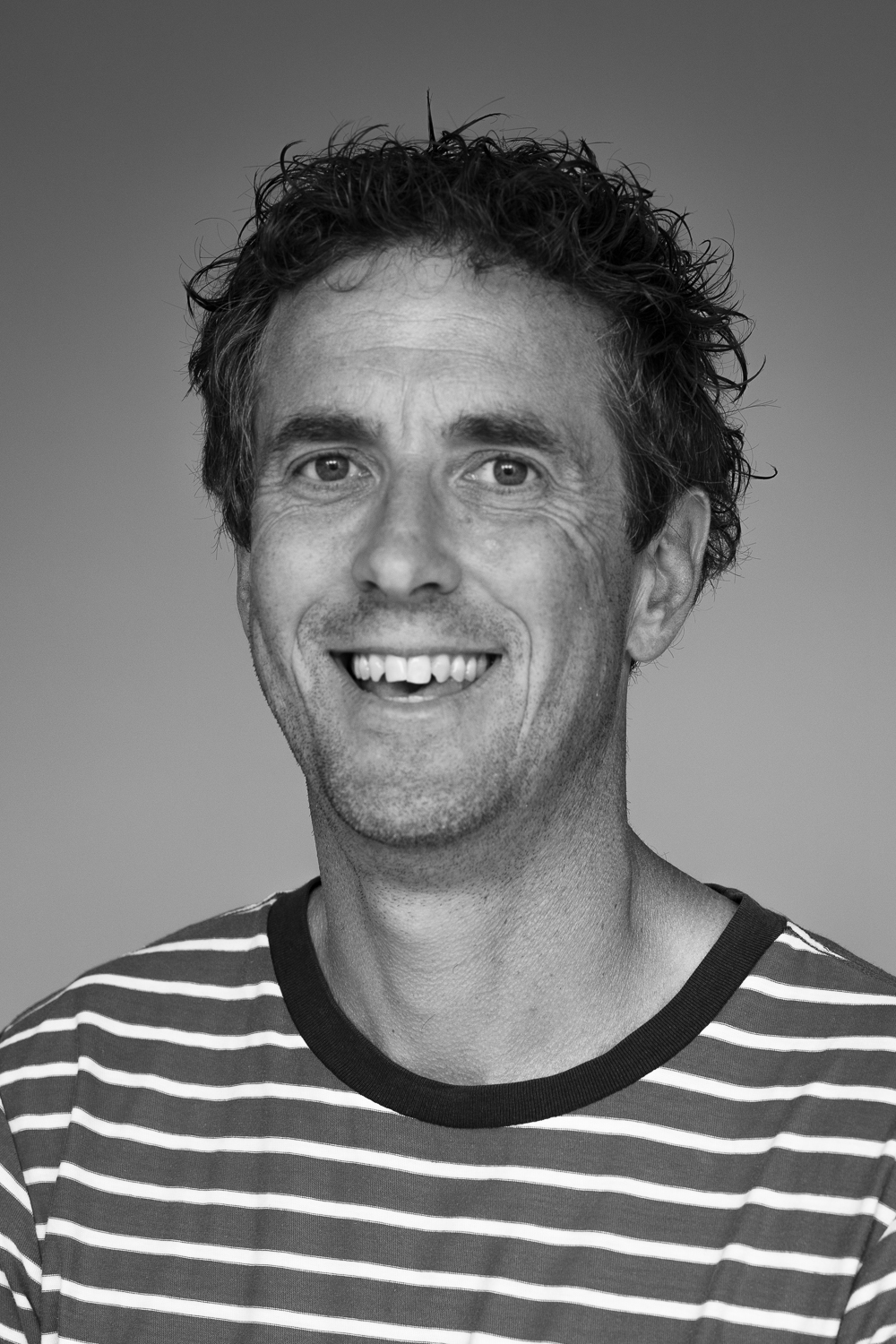 fotograaf in zwart wit kijkt trots en lachend in de camera